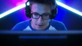 Professional gamer with glasses in front of a monitor with a headset on