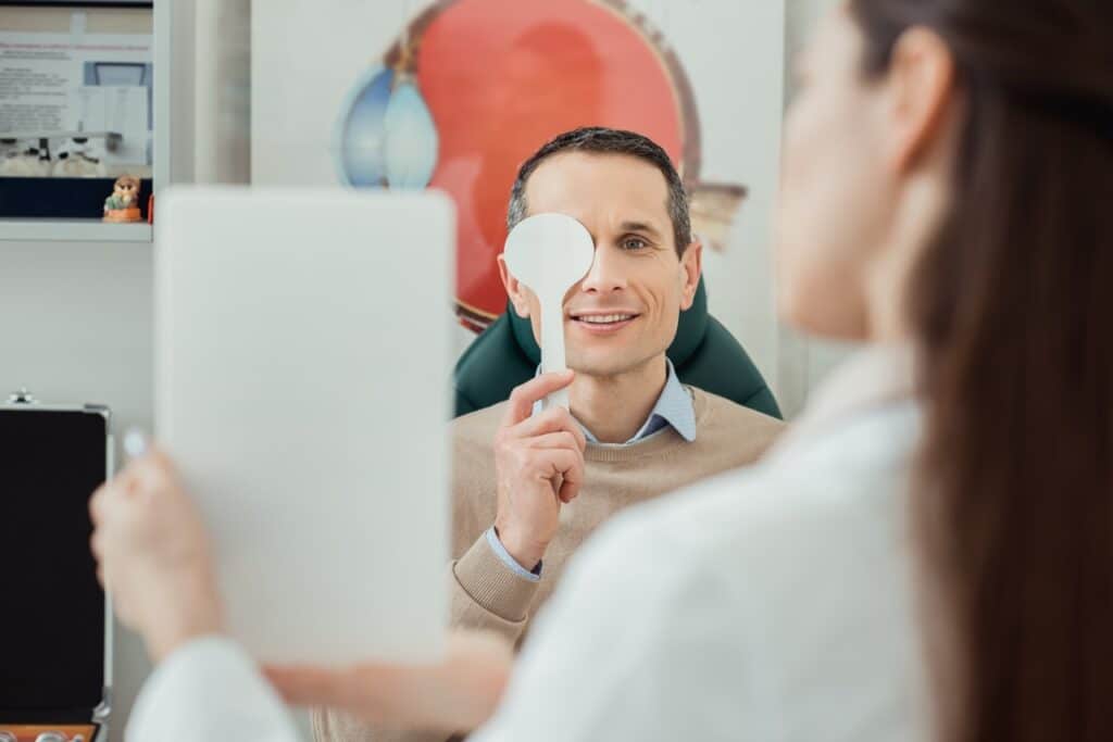 selective focus of smiling man getting eye examination by oculist in clinic