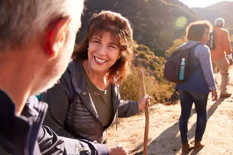 Older friends enjoying a hike on a sunny mountain trail