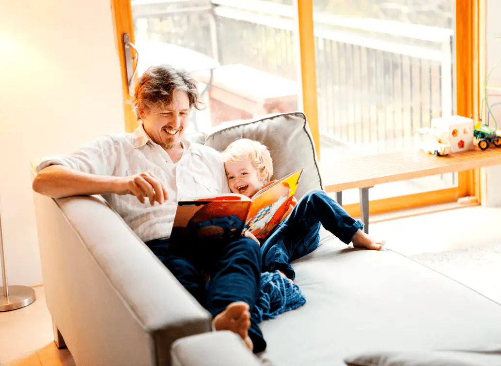 Father and child reading a picture book together at home